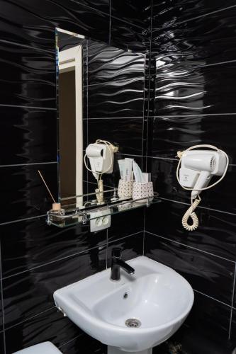 a black bathroom with a sink and a mirror at Cube House Osh in Osh