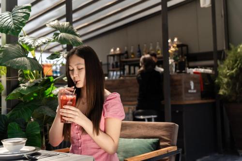 a girl sitting at a table drinking a drink at Cube House Osh in Osh
