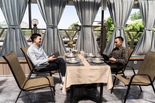 two men sitting at a table in a restaurant at Cube House Osh in Osh
