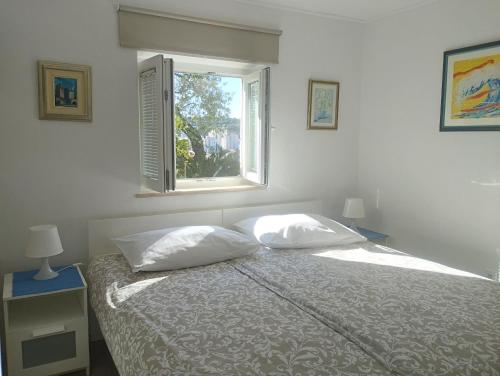 1 dormitorio con 1 cama con 2 almohadas y ventana en Apartment MARA MALA, en Dubrovnik