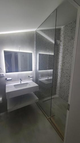 a bathroom with a sink and a shower and a mirror at Hotel Blue Eyes in Vlorë