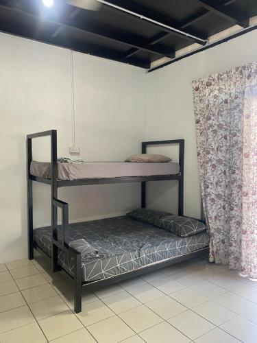 two bunk beds in a room with a curtain at Julian Homestay in Tuaran