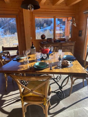 a large wooden table with plates and glasses on it at CHALET LUANE près de VALBERG in Beuil
