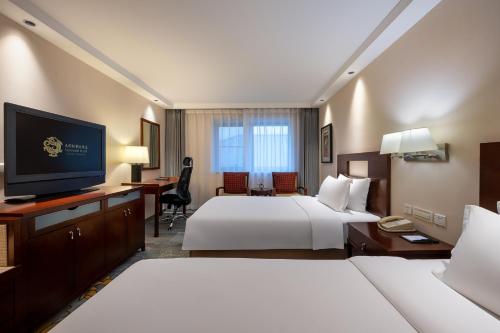a hotel room with two beds and a desk and a television at Sunworld Hotel Wangfujing in Beijing