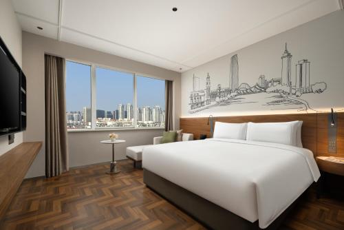ein Schlafzimmer mit einem großen weißen Bett und einem großen Fenster in der Unterkunft UrCove by Hyatt Tianjin West Railway STN in Tianjin