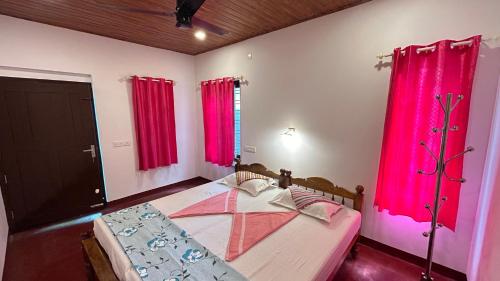 Schlafzimmer mit rosa Vorhängen und einem Bett in einem Zimmer in der Unterkunft Marari Sabari Home Stay in Mararikulam