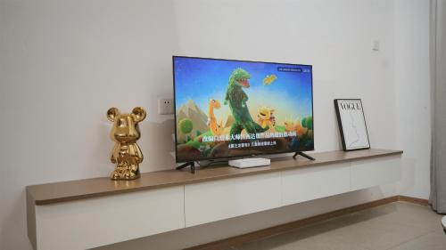 a flat screen tv on a shelf with a dinosaur on it at Serveyou International Apartment Hotel - Free Airport Pickup & Free Canton Fair shuttle & Paid City Tour in Zengcheng