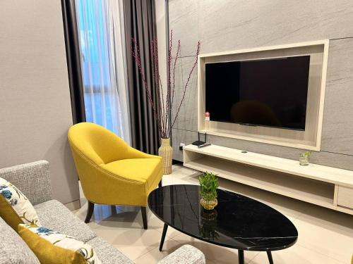 Societe by Bamboo Hospitality في كوالالمبور: غرفة معيشة مع تلفزيون وطاولة وكراسي صفراء