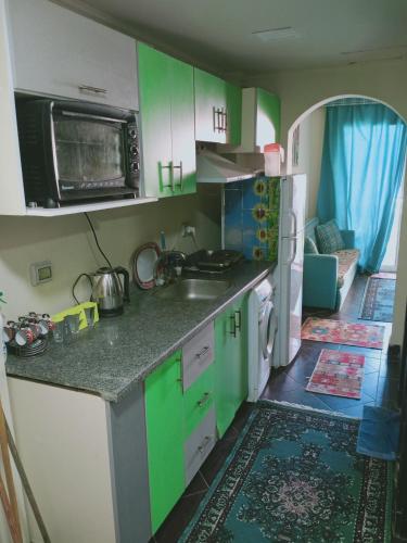 Kuchnia wyposażona jest w zielone i białe szafki oraz umywalkę. w obiekcie شاليه ارضي 48 م بورتو مطروح w mieście Marsa Matruh