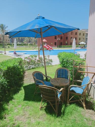 una mesa con sillas y una sombrilla junto a la piscina en شاليه ارضي 48 م بورتو مطروح en Marsa Matruh