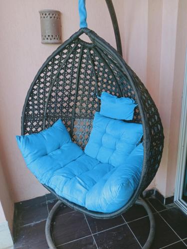 wiszący fotel z niebieskimi poduszkami w pokoju w obiekcie شاليه ارضي 48 م بورتو مطروح w mieście Marsa Matruh