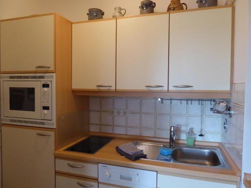 a kitchen with a sink and a microwave at Ferienwohnung Am Kräutergarten - mit Pool, Sauna und Garage in Missen-Wilhams