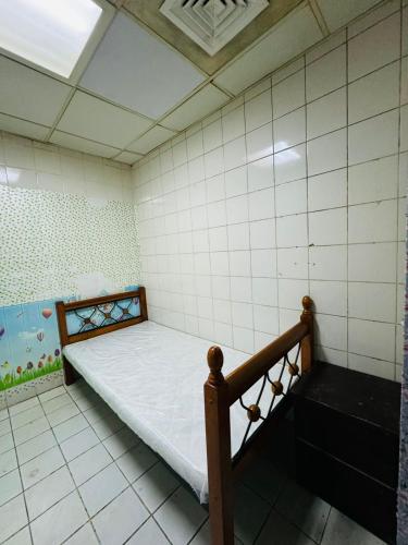 Cette petite chambre comprend un lit et un mur carrelé. dans l'établissement small room PM new location, à Abu Dhabi