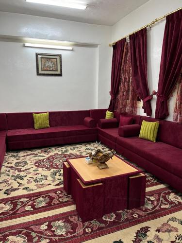 بيت ريفي في Muqammar: غرفة معيشة مع أرائك أرجوانية وطاولة