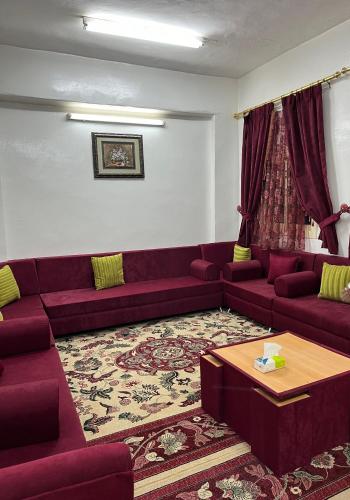 بيت ريفي في Muqammar: غرفة معيشة مع أرائك أرجوانية وطاولة