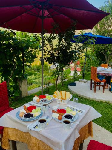 een tafel met borden eten erop met een paraplu bij Villa Silvester in Hardedaj
