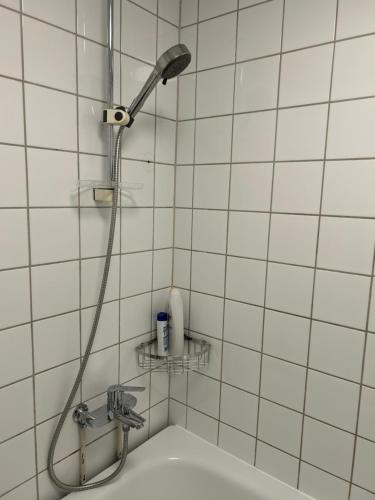 a shower with a shower head in a white tiled bathroom at National Theater Dormitory Mixed in Oslo