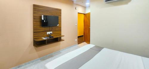 a room with a bed and a tv on a wall at Hotel Nova Blue in Ahmedabad