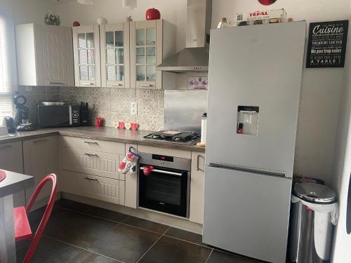 Il comprend une cuisine équipée d'un réfrigérateur blanc et d'une cuisinière. dans l'établissement Maison d Angele 4 chambres, à Chambray-lès-Tours