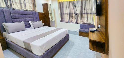 a bedroom with a bed with a purple headboard at Hotel Nova Blue in Ahmedabad