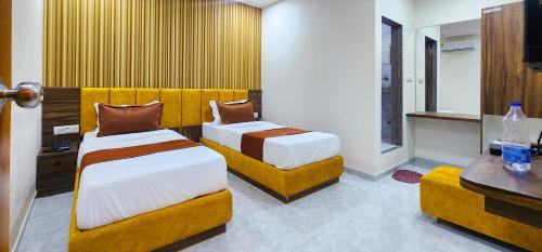 a hotel room with two beds and two chairs at Hotel Nova Blue in Ahmedabad