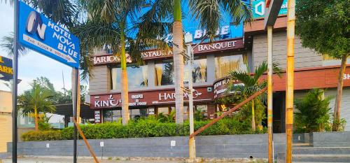 a building with palm trees in front of it at Hotel Nova Blue in Ahmedabad