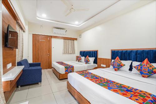 a hotel room with two beds and a blue chair at FabHotel HK Villa in Vadodara