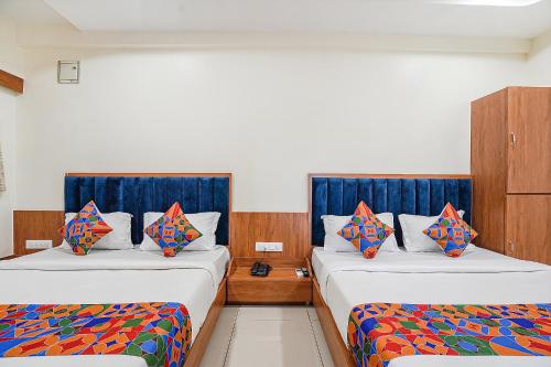 2 Betten in einem Hotelzimmer mit blauen Vorhängen in der Unterkunft FabHotel HK Villa in Vadodara