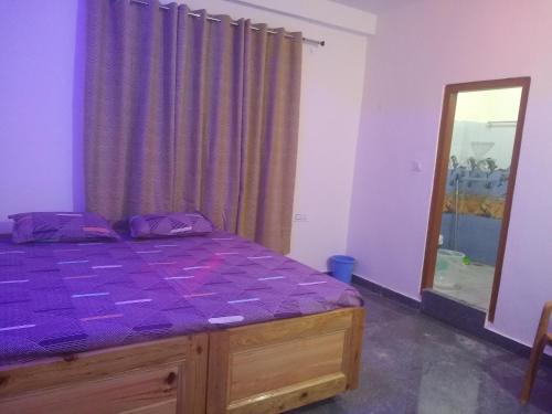 een slaapkamer met een bed met paarse lakens en een spiegel bij Tabassum guest house in Kasol