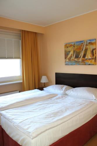 a bedroom with a large white bed with a window at Wiking Hotel in Henstedt-Ulzburg