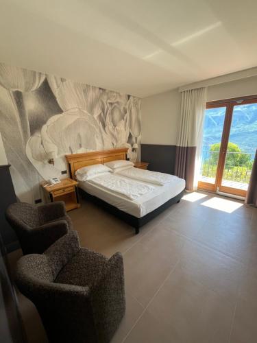 a bedroom with a bed and two chairs at Villa Selene in Tremosine Sul Garda