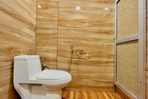 a bathroom with a toilet and wooden walls at Goroomgo Hotel Shining Star Resort - Prime Location - Excellent Service in Lāhri
