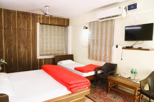 um quarto com 2 camas, uma secretária e uma televisão em Sikaria Homes em Ranchi