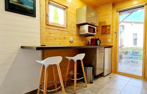une cuisine avec deux tabourets et un comptoir avec un four micro-ondes dans l'établissement Cabane côté jardin, à Toulouse
