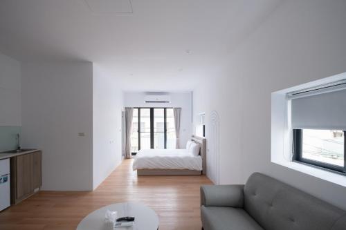 a white living room with a couch and a bed at Suite 宿特 I 鄰近武聖夜市 in Hsin-t'ing