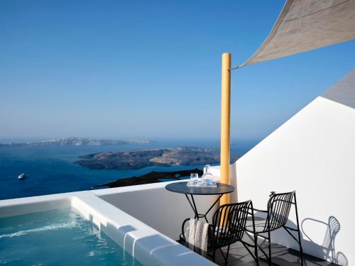 a table and chairs on a balcony with a view of the ocean at Stella Rocca A Mare in Imerovigli