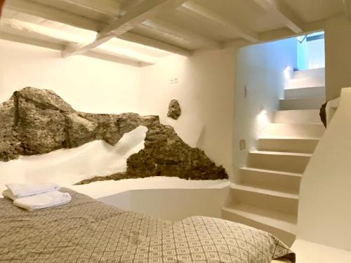 a bedroom with a bed and a rock wall at The Bellhouse Kranidi in Kranidi