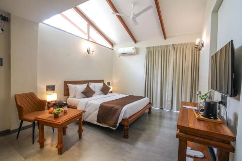a bedroom with a bed and a table and a tv at Toyam by Orchid Hotels in Bhor