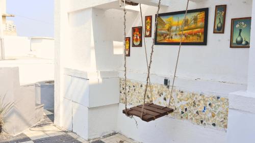 a swing hanging from a white wall with paintings at Stylish 3BHK Penthouse W/Terrace Steps from EON IT in Pune