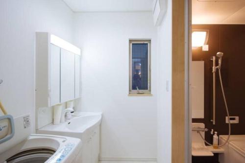 a white bathroom with a washing machine in it at 楓 in Osaka