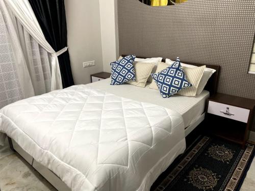 um quarto com uma cama com almofadas azuis e brancas em Blue core em Ernakulam