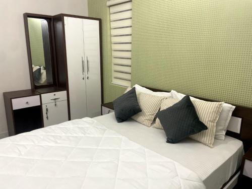 um quarto com uma cama branca com almofadas e um espelho em Blue core em Ernakulam