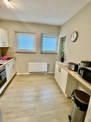a kitchen with white cabinets and a clock on the wall at Ferienhaus Dobias in Kelberg