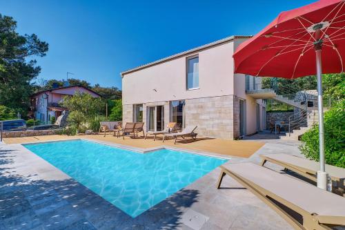 a house with a swimming pool and a red umbrella at VILLA RITA ARTaTORE in Mali Lošinj