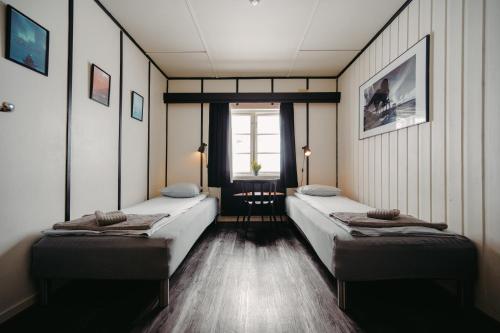 two beds in a room with a window at Gjestehuset 102 in Longyearbyen