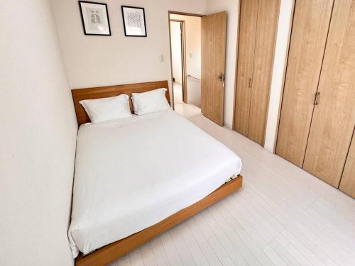 a bedroom with a bed with white sheets and wooden furniture at 楓 in Osaka