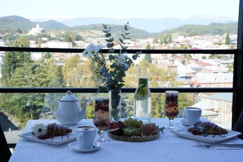 einen Tisch mit Teller mit Lebensmitteln und ein Fenster mit Aussicht in der Unterkunft Hotel Panoramic in Kutaissi