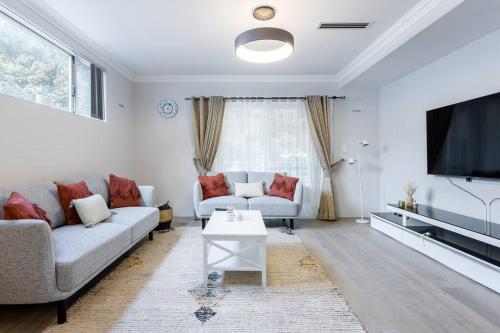 a living room with a couch and a tv at Executive CBD Perth House 4BR 3BA 2Pk SLEEP 8! in Perth