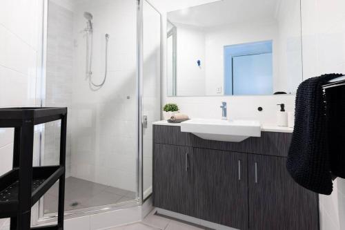 a white bathroom with a sink and a shower at Executive CBD Perth House 4BR 3BA 2Pk SLEEP 8! in Perth