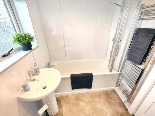 a white bathroom with a sink and a bath tub at Terrance House, modern, spacious in Carlisle